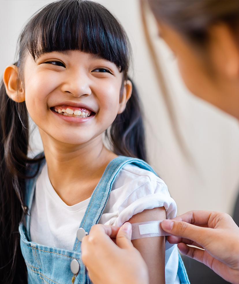 Photo of a doctor putting a bandaid on a child's arm after an appointment for childhood immunizations