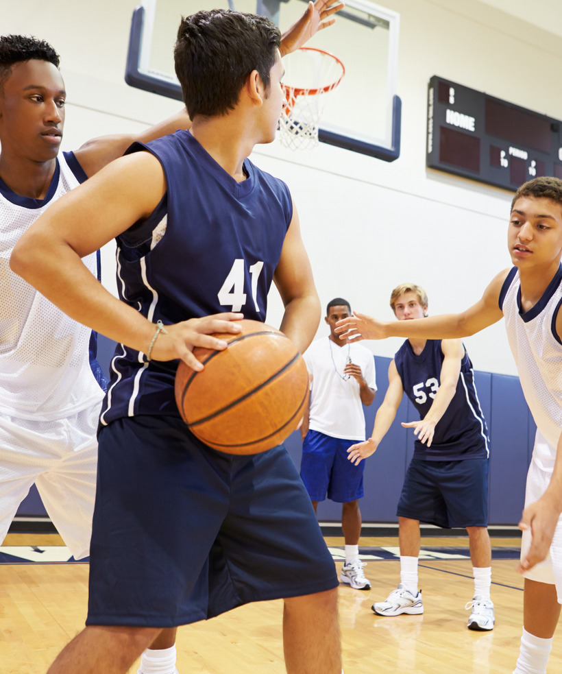 Photo of teenage boys playing in a basketball league at school