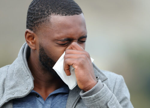 Photo of a man with cold coughing into a tissue